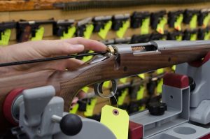 A cleaning rod with a bore brush being used to clean the inside of a lever action rifle’s barrel.