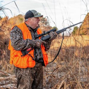 A hunter using a lever action rifle while adhering to local hunting regulations, including proper licensing and safety gear.