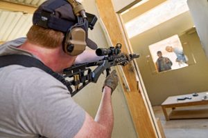 A lever action rifle positioned against a target at a shooting range, illustrating the rifle’s limited range.