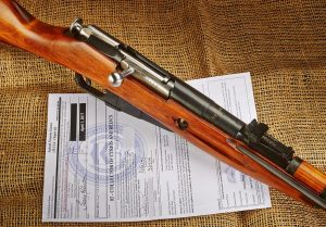 An antique lever action rifle displayed in a gun shop, with accompanying legal documentation for buyers to review.